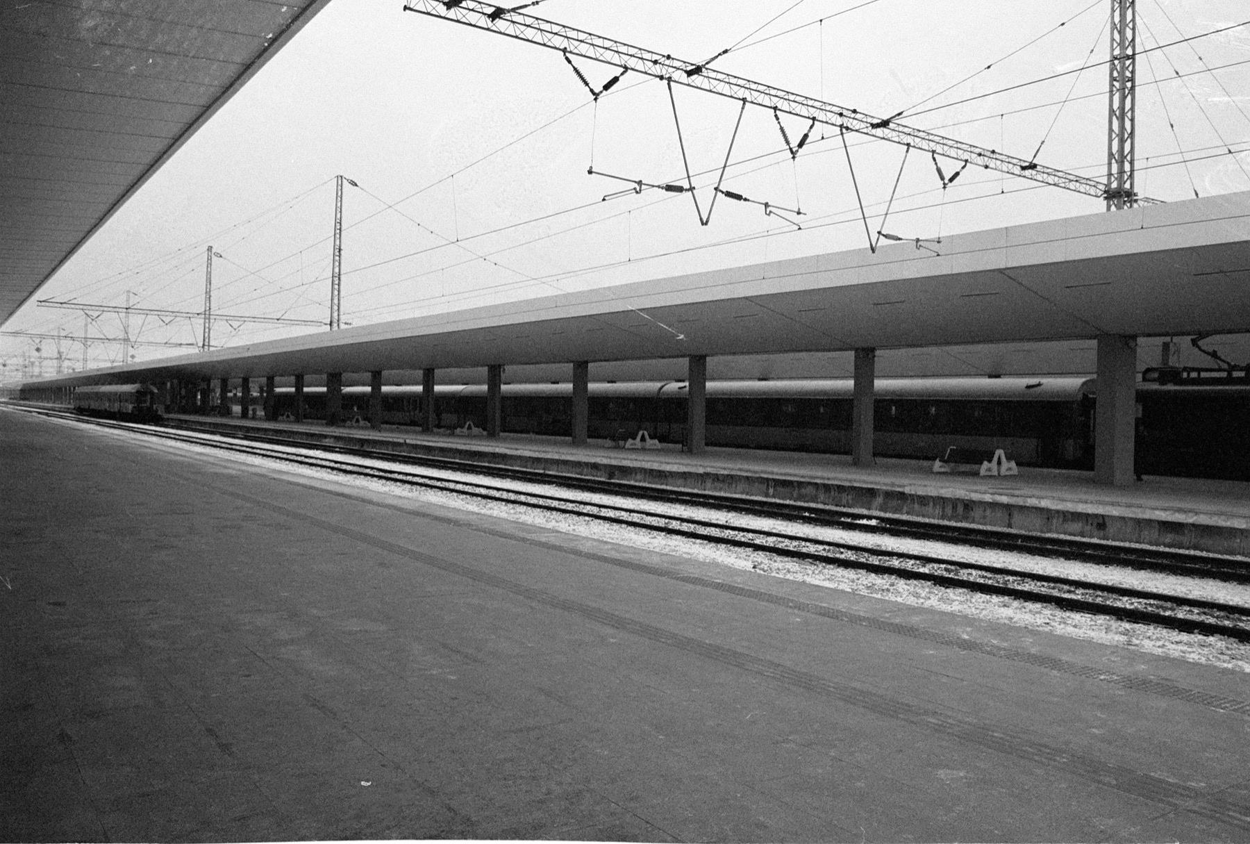 Analogue black and white photograph of a quiet railway platform